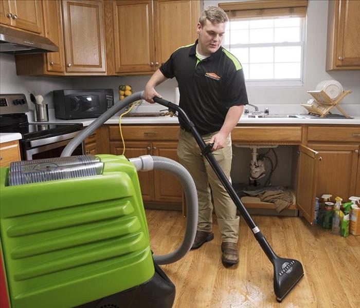 SERVPRO Technician using a floor wand to extract water.
